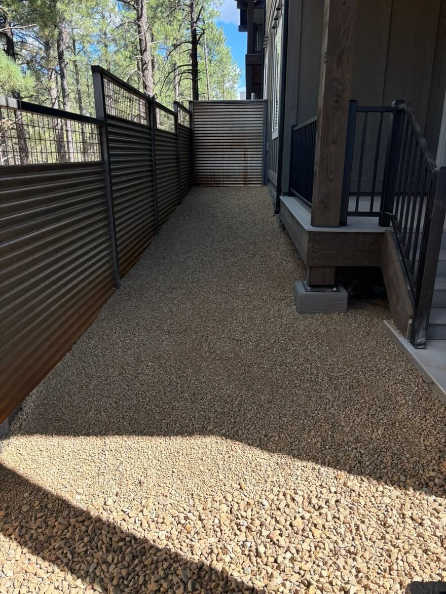 Clean decomposed-granite side yard with metal fencing on a Flagstaff property